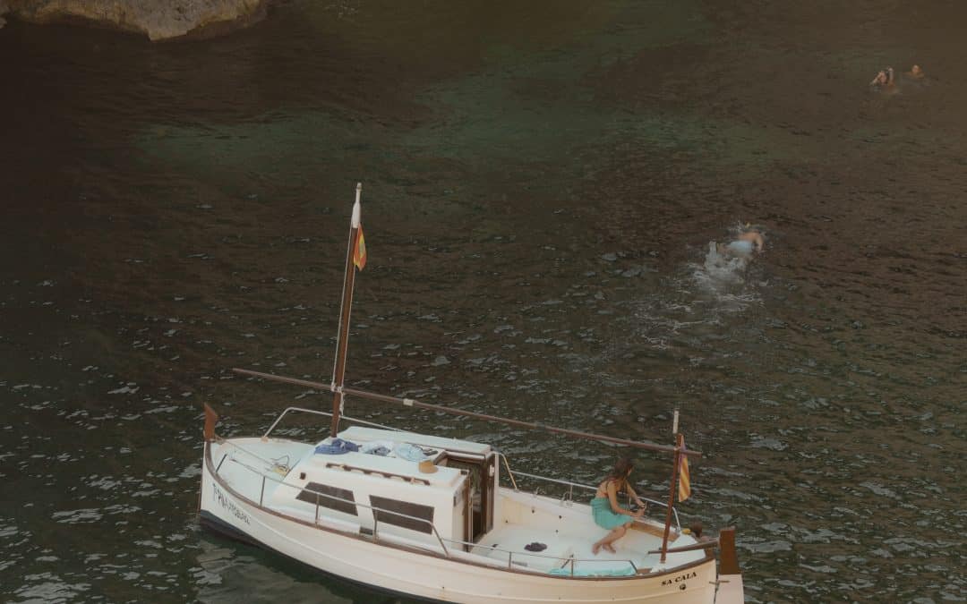 Picture of a boat in front of a marine cave with someone swimming from the boat towards the entrance of the cove.